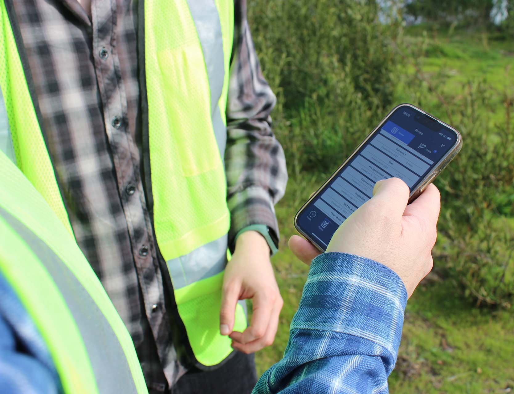 Two field workers using the Eskuad app on their mobile device