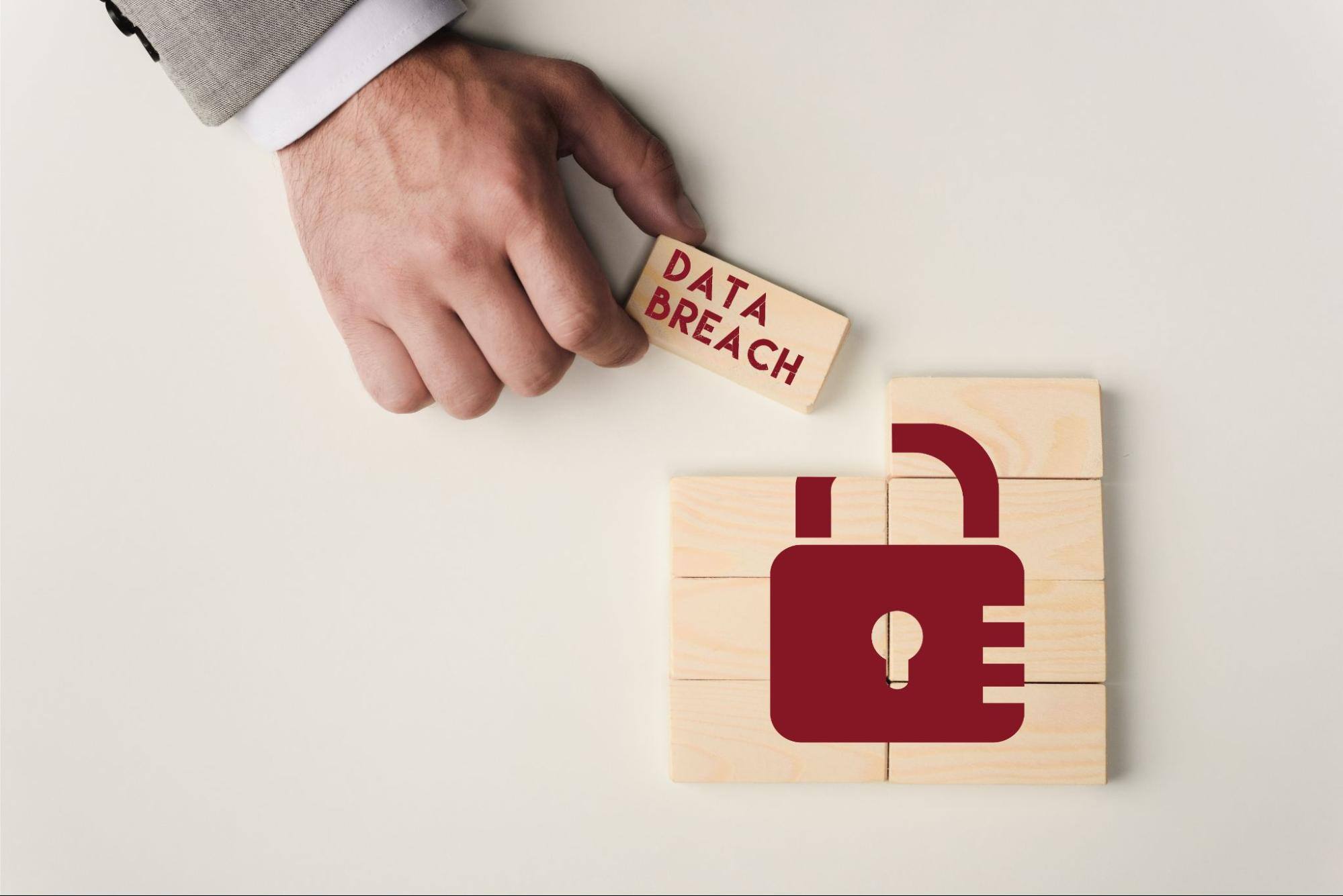 Man holding a wooden block that says “data breach” next to blocks with an image of a lock on them. 